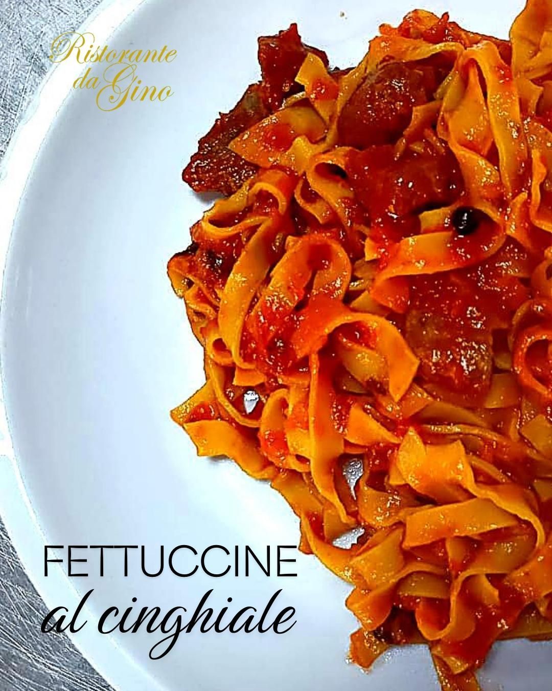 Fettuccine al cinghiale in ricco sugo di pomodoro su piatto bianco