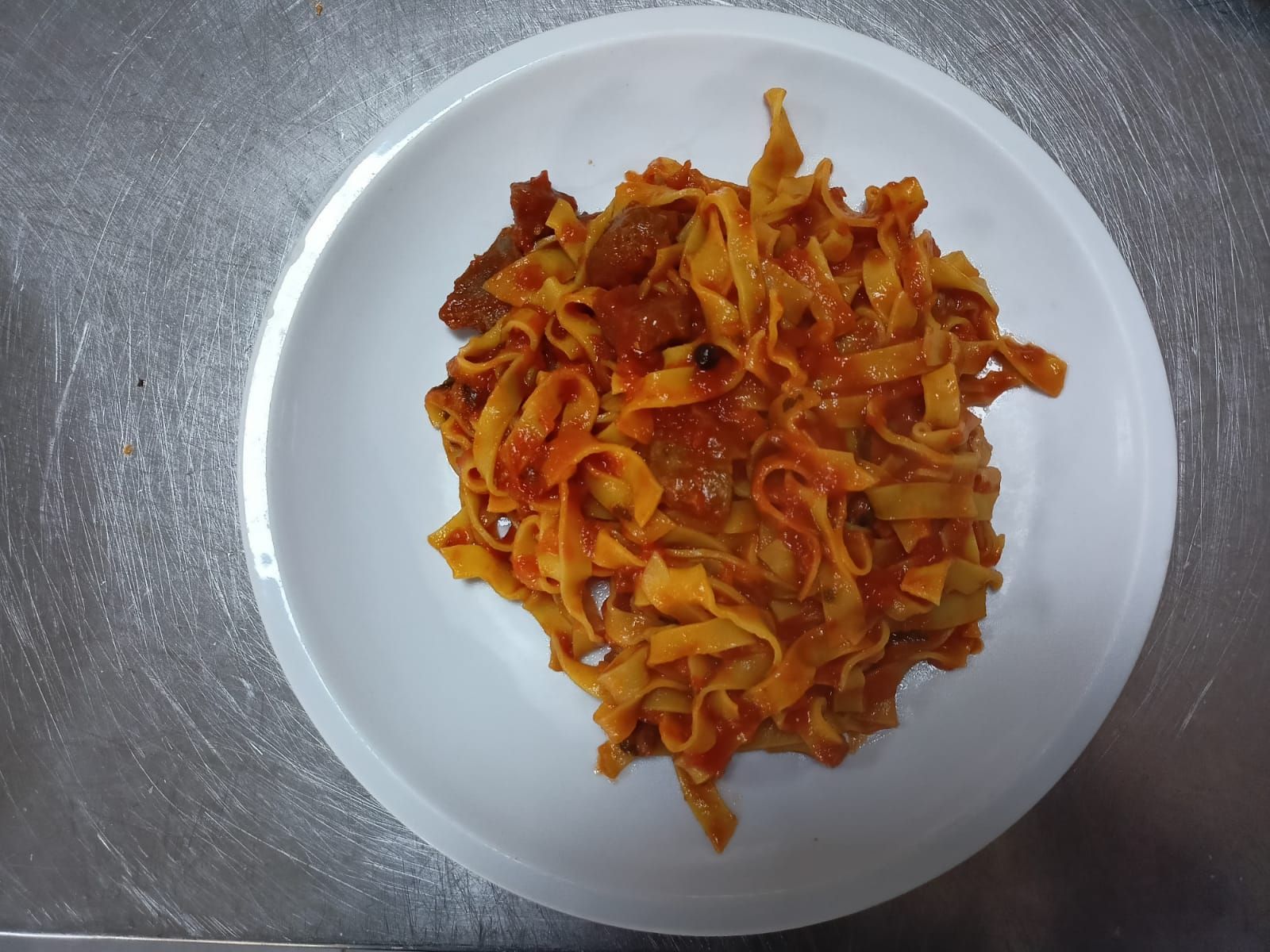 Piatto di pasta rosso-arancio su una superficie argentata