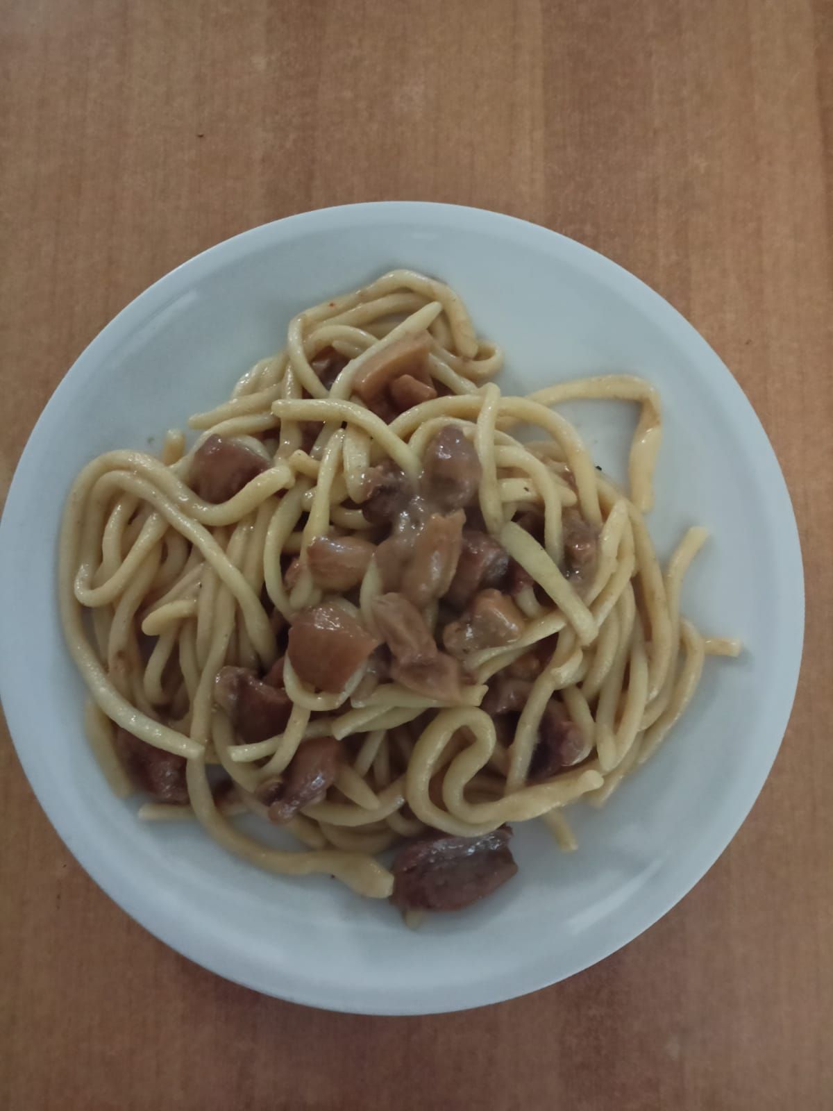 Un piatto di spaghetti ai funghi su un tavolo di legno.