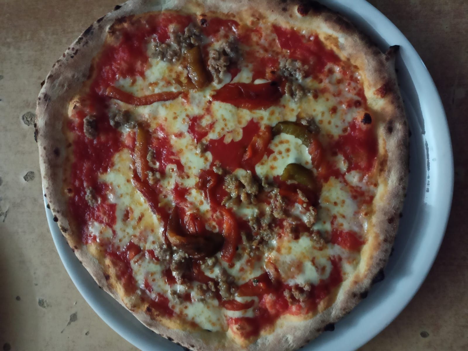 Pizza al formaggio con salsa rossa su un piatto bianco, vista dall'alto.