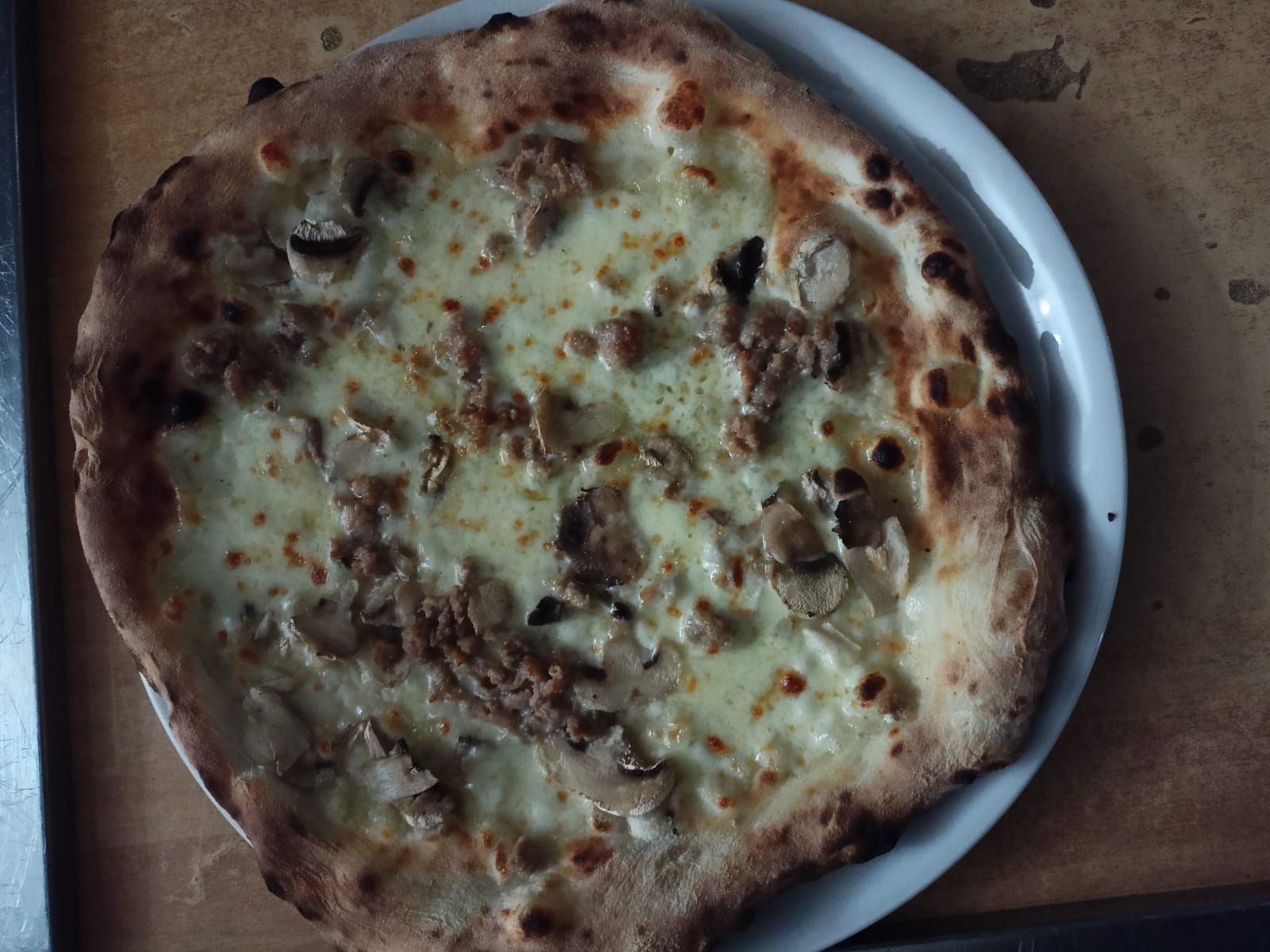 Una pizza al formaggio cotta al forno su un piatto bianco, vista dall'alto.