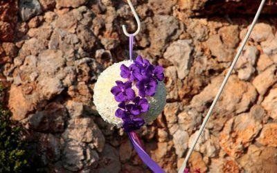 Ornamento floreale viola appeso a un muro di pietra marrone grezza.