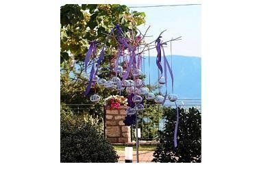 Un palo ad arco, decorato con nastri viola, sovrasta un sentiero del giardino, con sullo sfondo una vista di montagne azzurre.