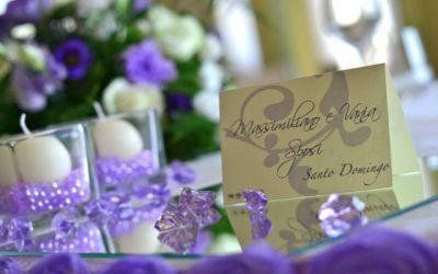 Allestimento della tavola con fiori viola, segnaposto e candele decorative sul tavolo del ricevimento di nozze.