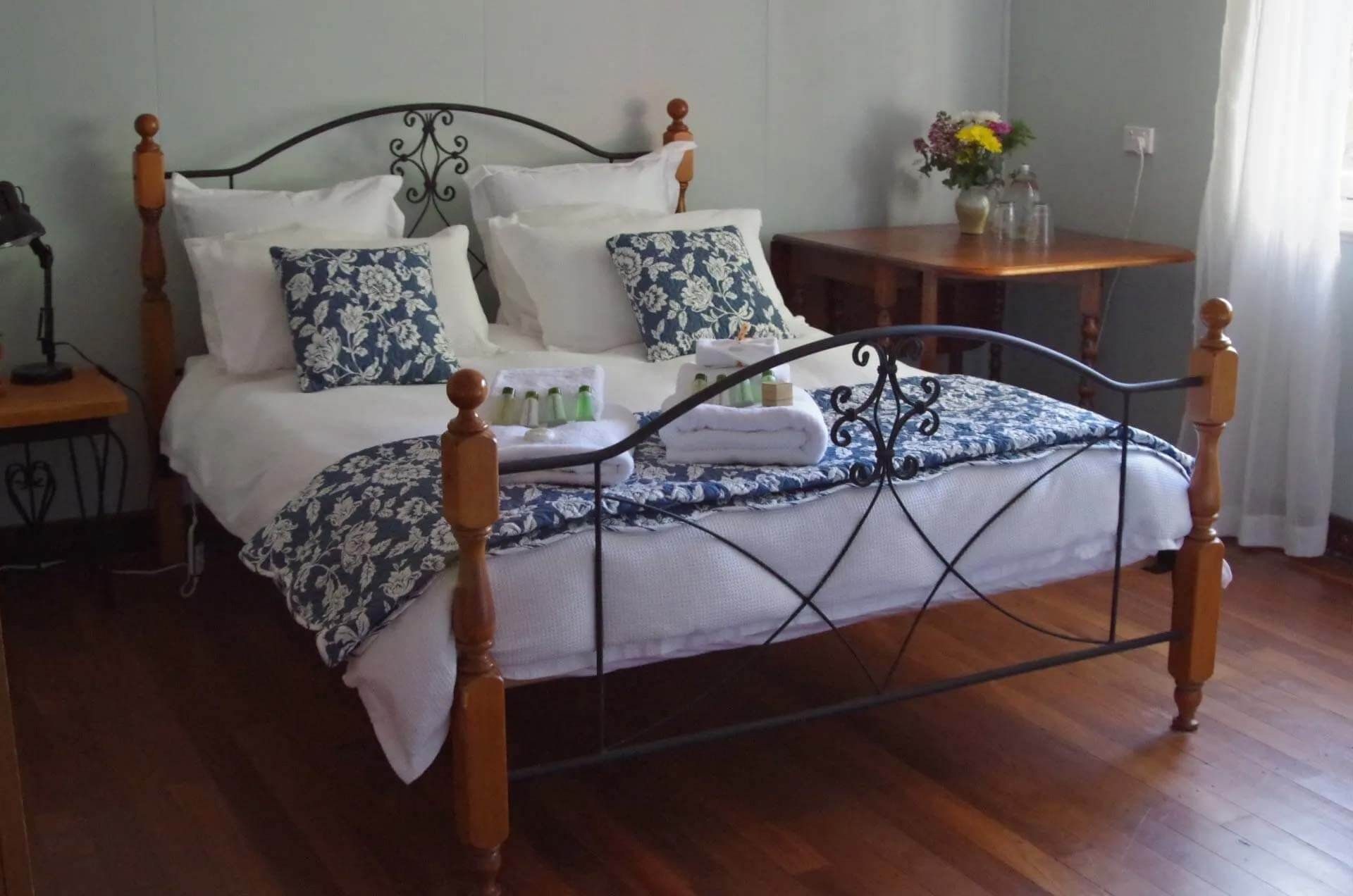 Budget accommodation in Narrogin with an ornate metal bed, patterned cushions and timber flooring.