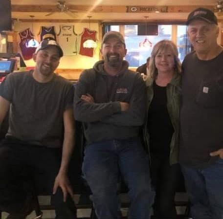 Four people posing together in a cozy bar, smiling at the camera.