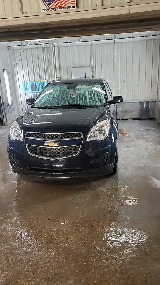 Dark blue sedan parked indoors on a wet concrete floor in a garage.