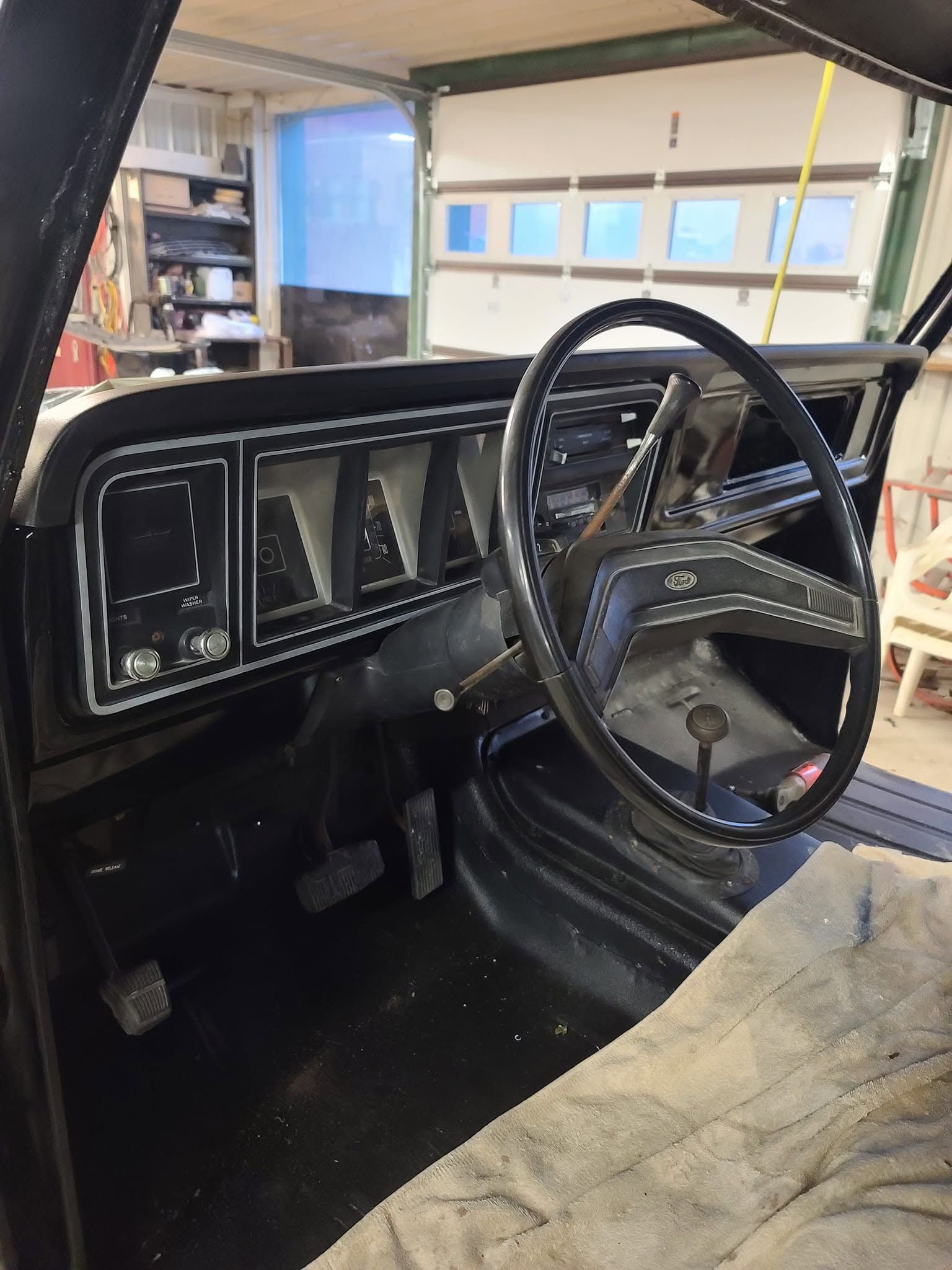 Vintage truck interior with black dashboard and steering wheel inside a garage