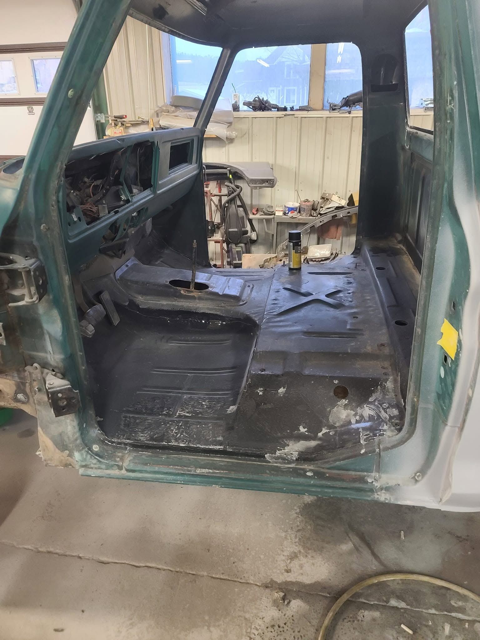 Burned vehicle interior with charred dashboard and seats, viewed through an open side door
