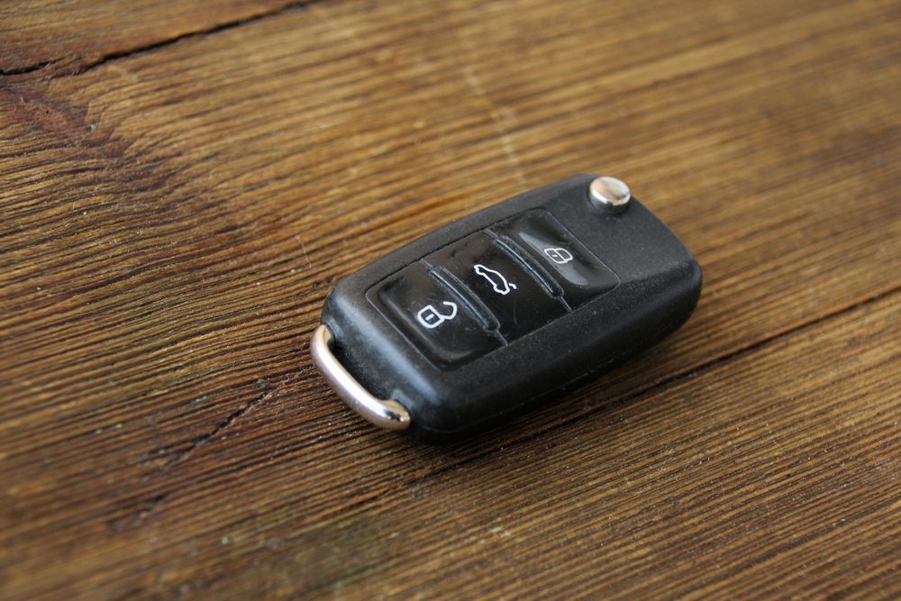 Black Car Key Fob With Silver Edge on a Wooden Surface — Battery Assist Brisbane in Warner, QLD