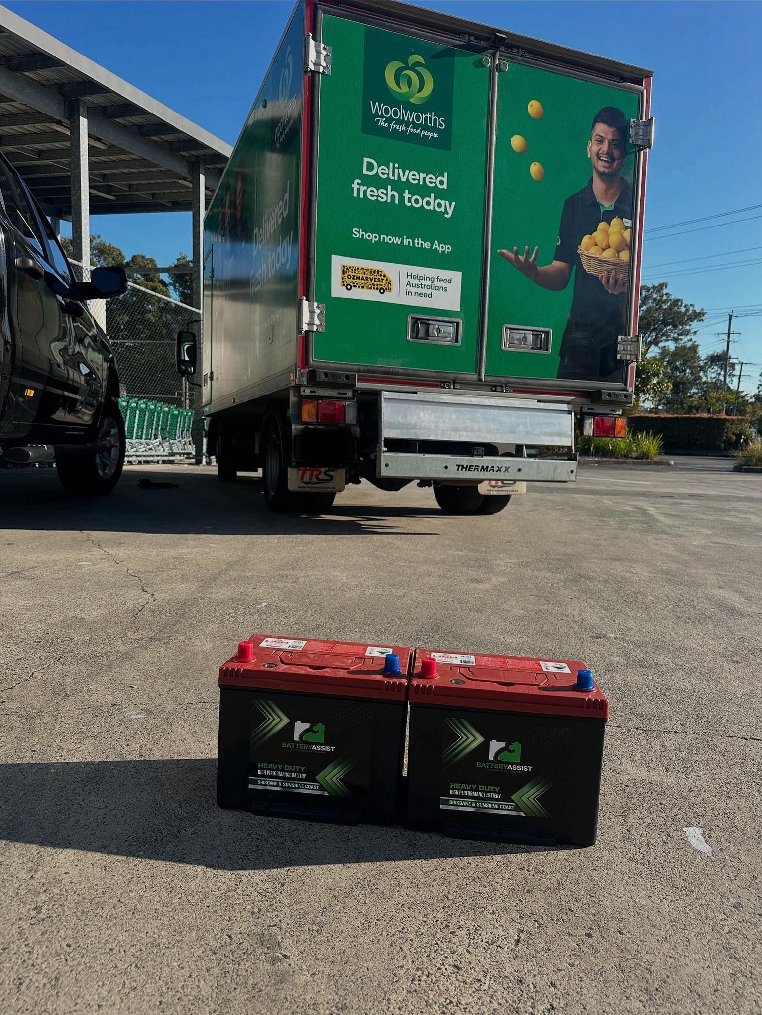 Two Car Batteries in Front of a Green Delivery Truck — Battery Assist Brisbane in Bracken Ridge, QLD