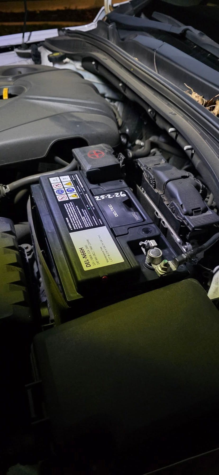Car Battery in an Engine Bay With a Black Cover and Warning Labels — Battery Assist Brisbane in Maroochydore, QLD