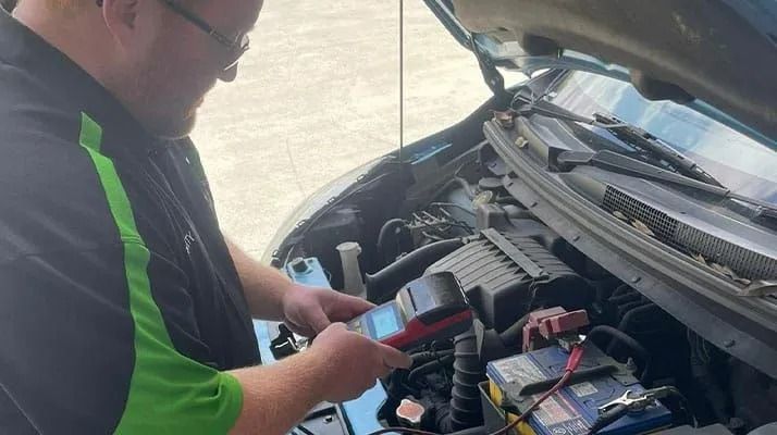 Person Using a Red Device to Test a Car Battery — Battery Assist Brisbane in Chermside, QLD