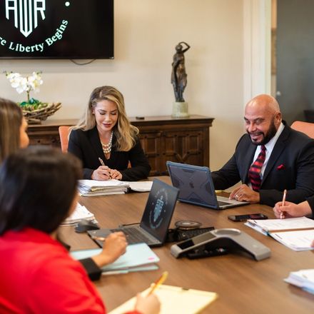 Business meeting in a conference room with four people around a table, using laptops and papers.