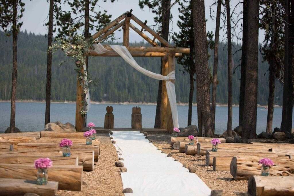 A wedding ceremony is taking place in the woods near a lake.