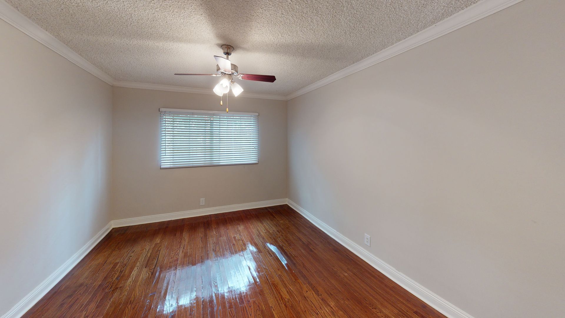 Empty room with hardwood floors, a window, and a ceiling fan.