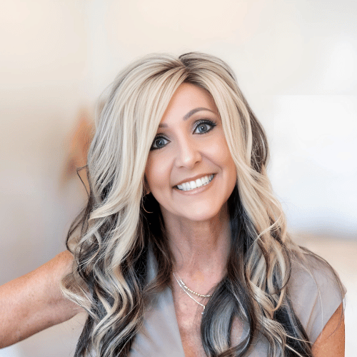 A woman with long blonde and black hair is smiling for the camera.