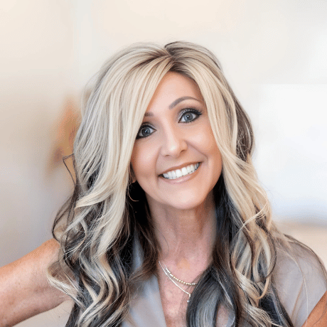 A woman with long blonde and black hair is smiling for the camera.