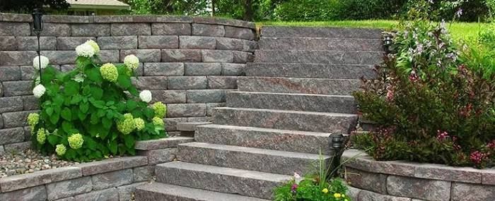 Stone garden steps beside stone retaining walls and flowering shrubs
