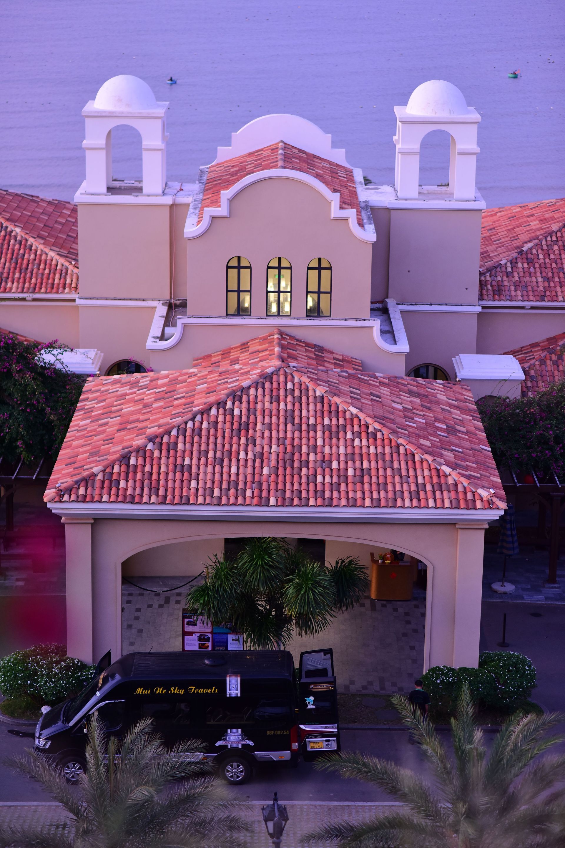 Spanish-style house with red tile roofs, arched entry, and a black truck parked in the driveway
