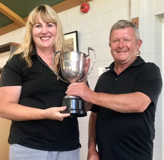 A man and a woman are holding a trophy and smiling