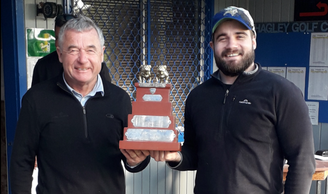 Two men are standing next to each other holding a trophy.