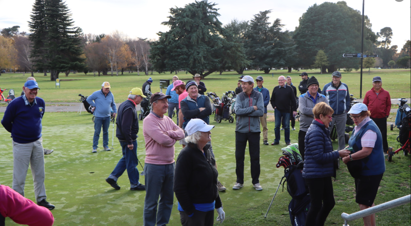 A group of people are standing on a golf course.