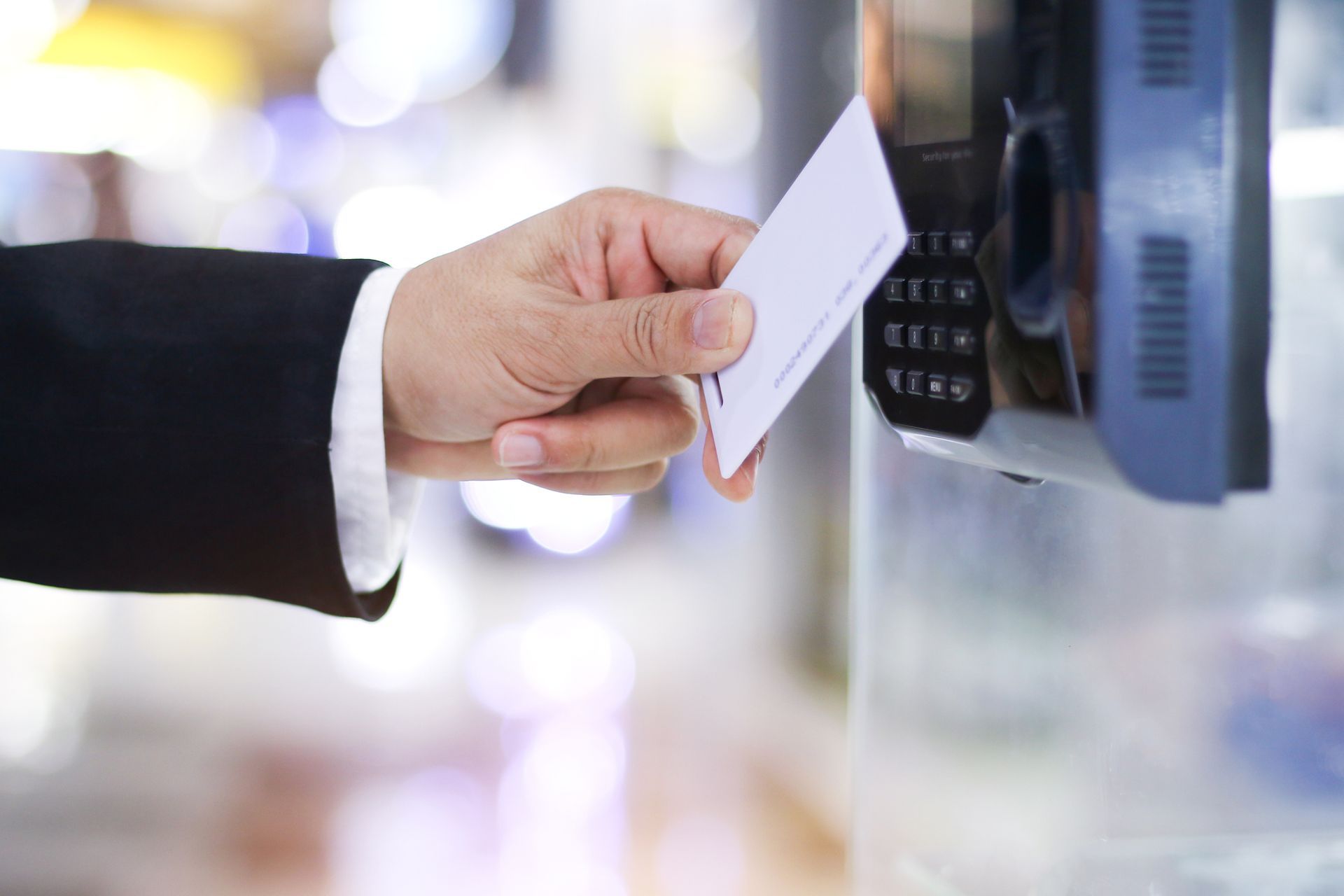A man in a suit swiping a key card at a security system