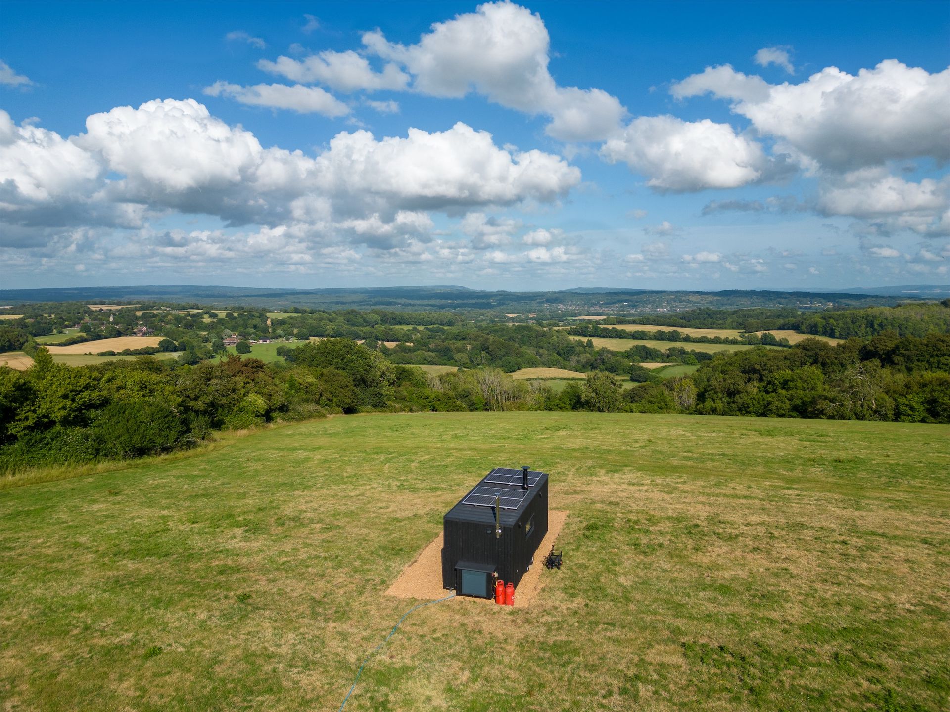 Off-grid cabin with sweeping views of South Downs hills under bright blue skies.