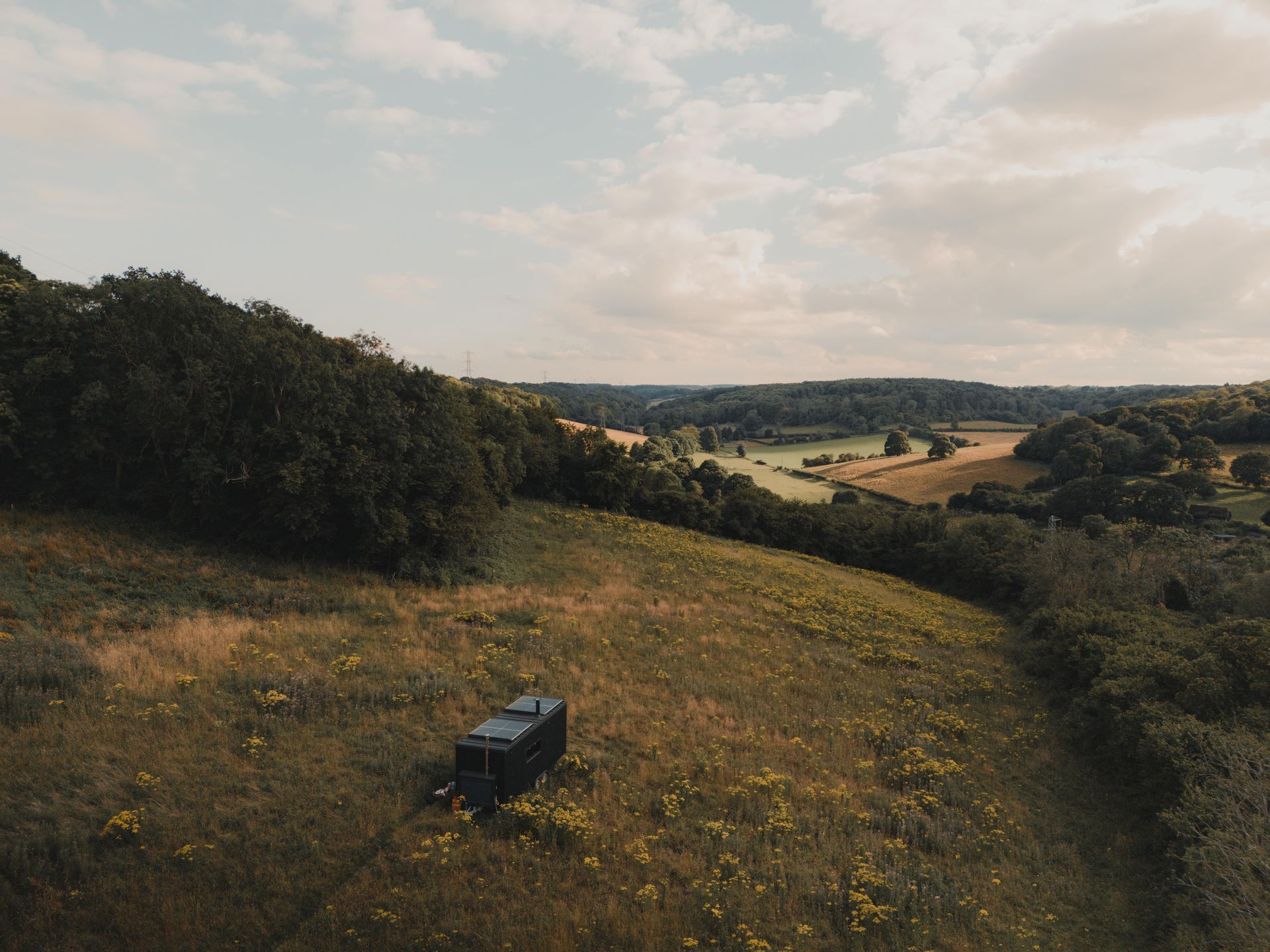 Panoramic view of Canterbury countryside with open fields and distant hills under cloudy sky.