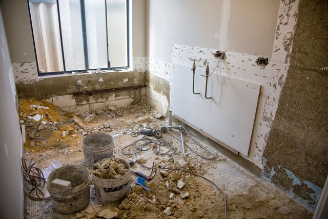 A bathroom under construction with buckets of dirt on the floor.