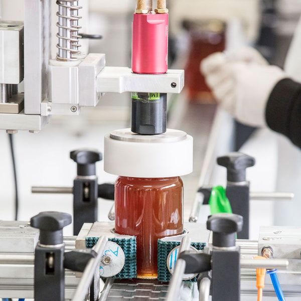 A photo of a jar of honey being filled at a food production facility