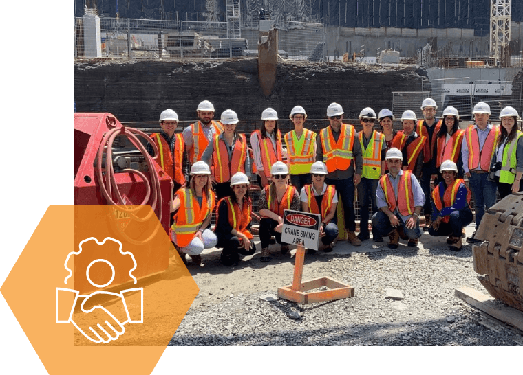 A group of construction workers are posing for a picture on a construction site.