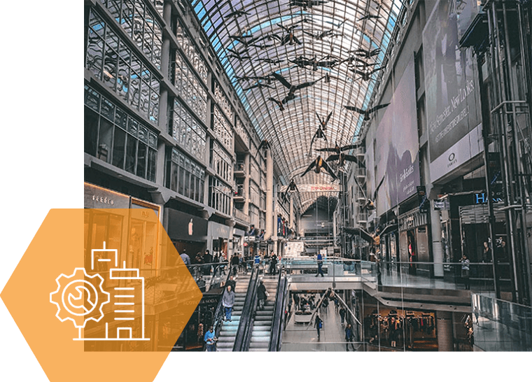 A large shopping mall with a glass ceiling and escalators.