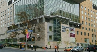 A large building with a lot of windows is on the corner of a city street.