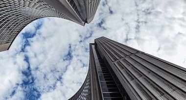 Looking up at a group of tall buildings against a cloudy sky.
