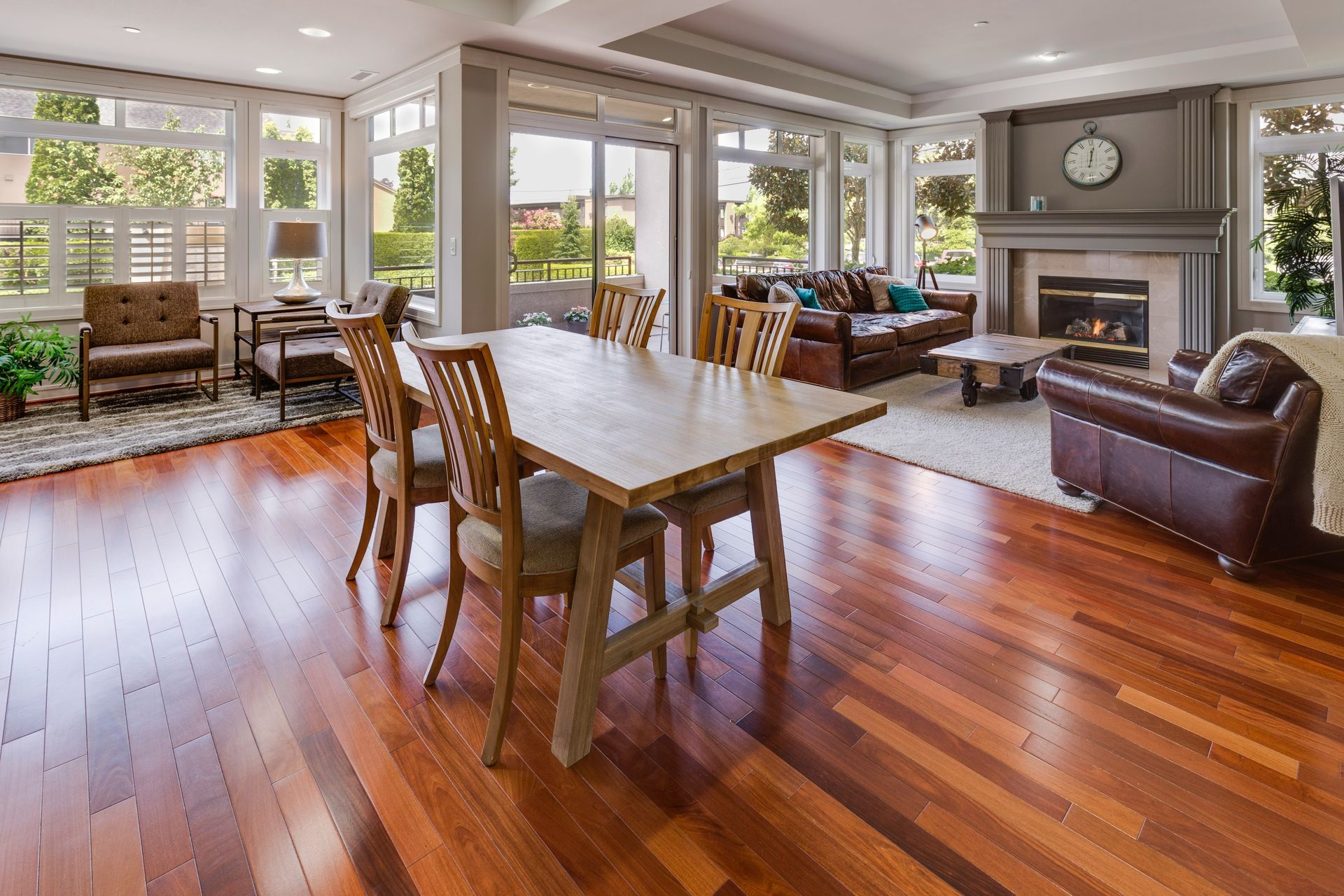 Spacious living room with hardwood floors, large dining table, fireplace, and bright windows.