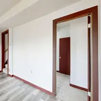 Empty white hallway with open doorways and brown trim, showing a bright interior space