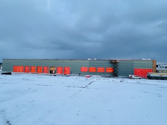 Bâtiment industriel enneigé aux portes orange sous un ciel nuageux