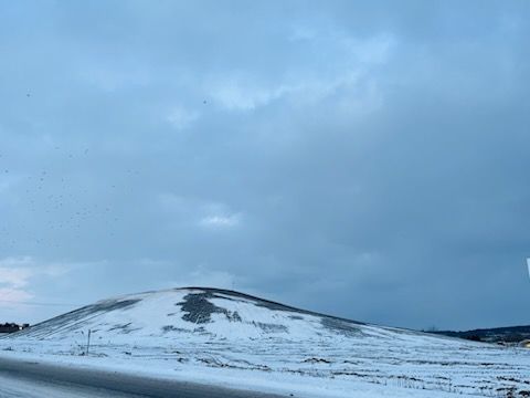 Colline enneigée sous un ciel bleu nuageux