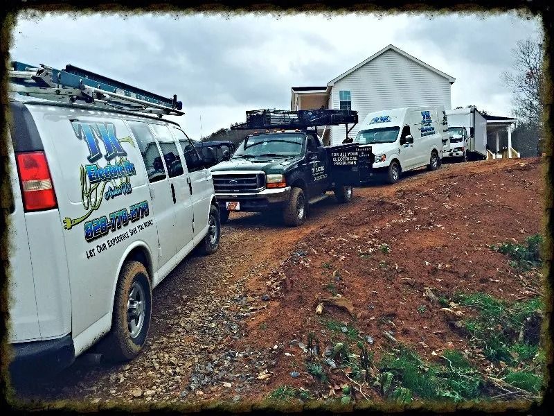 Three work trucks parked in a row on a dirt construction site in front of a white house.