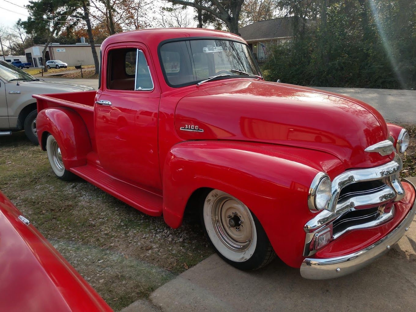 An antique, red pickup truck in a parking lot