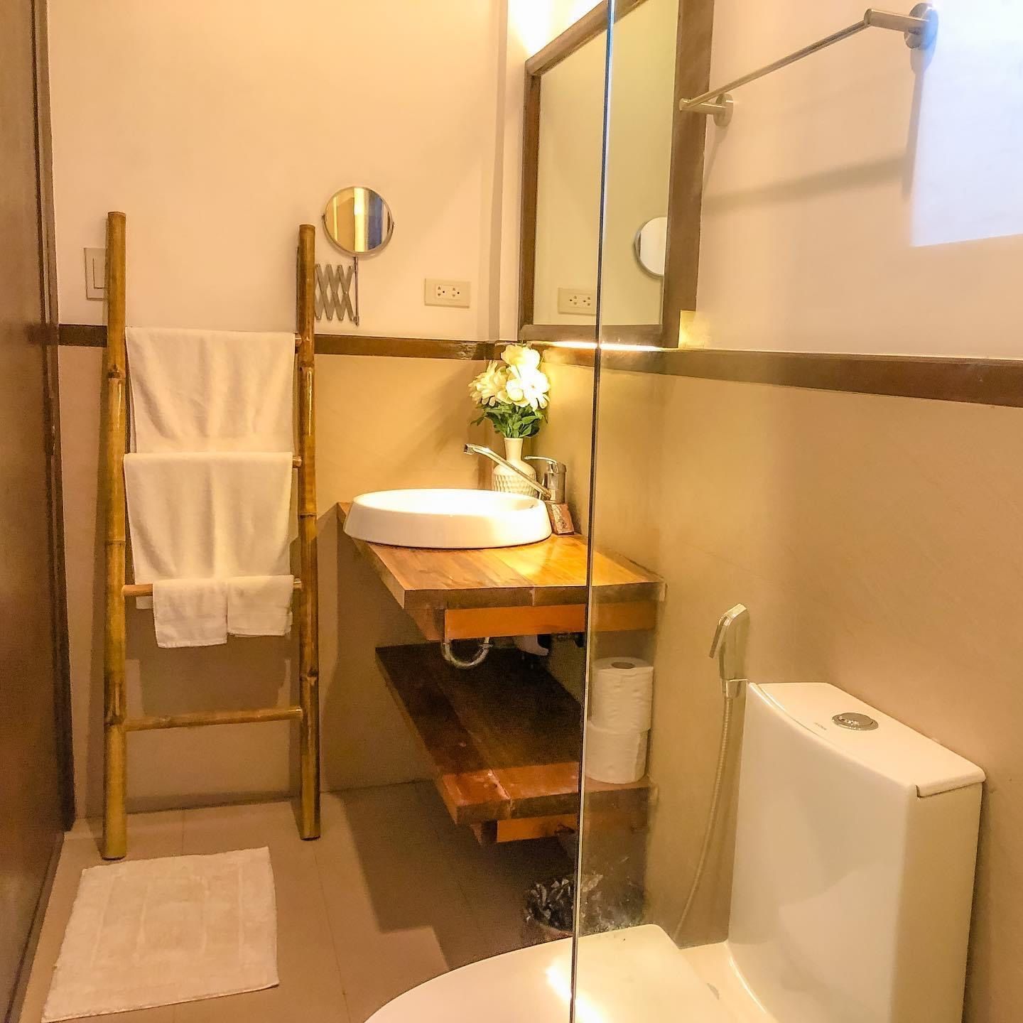 Modern bathroom with wooden sink vanity, ladder towel rack, mirror, and shower area