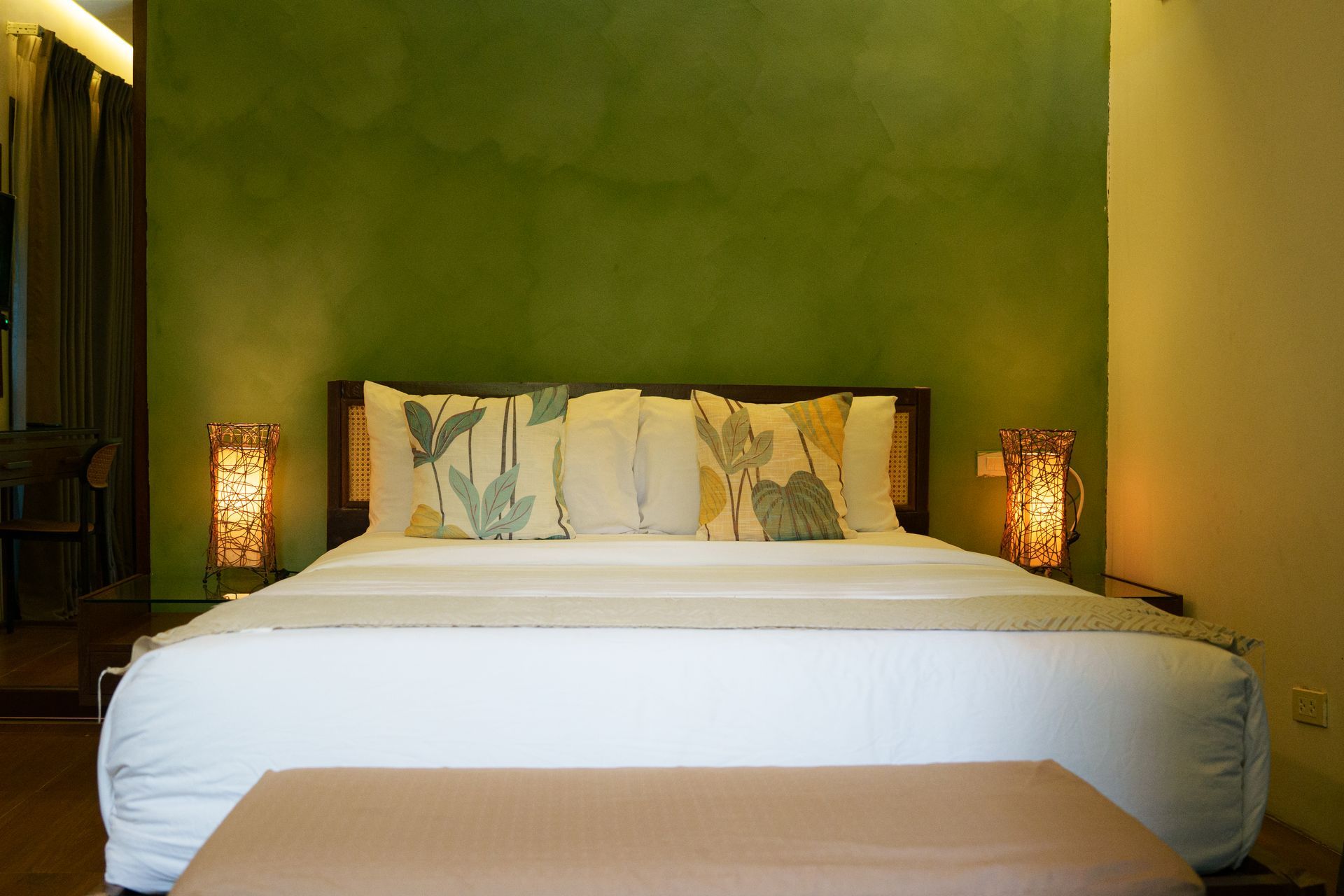 Modern bedroom with a white bed, green accent wall, and warm bedside lamps