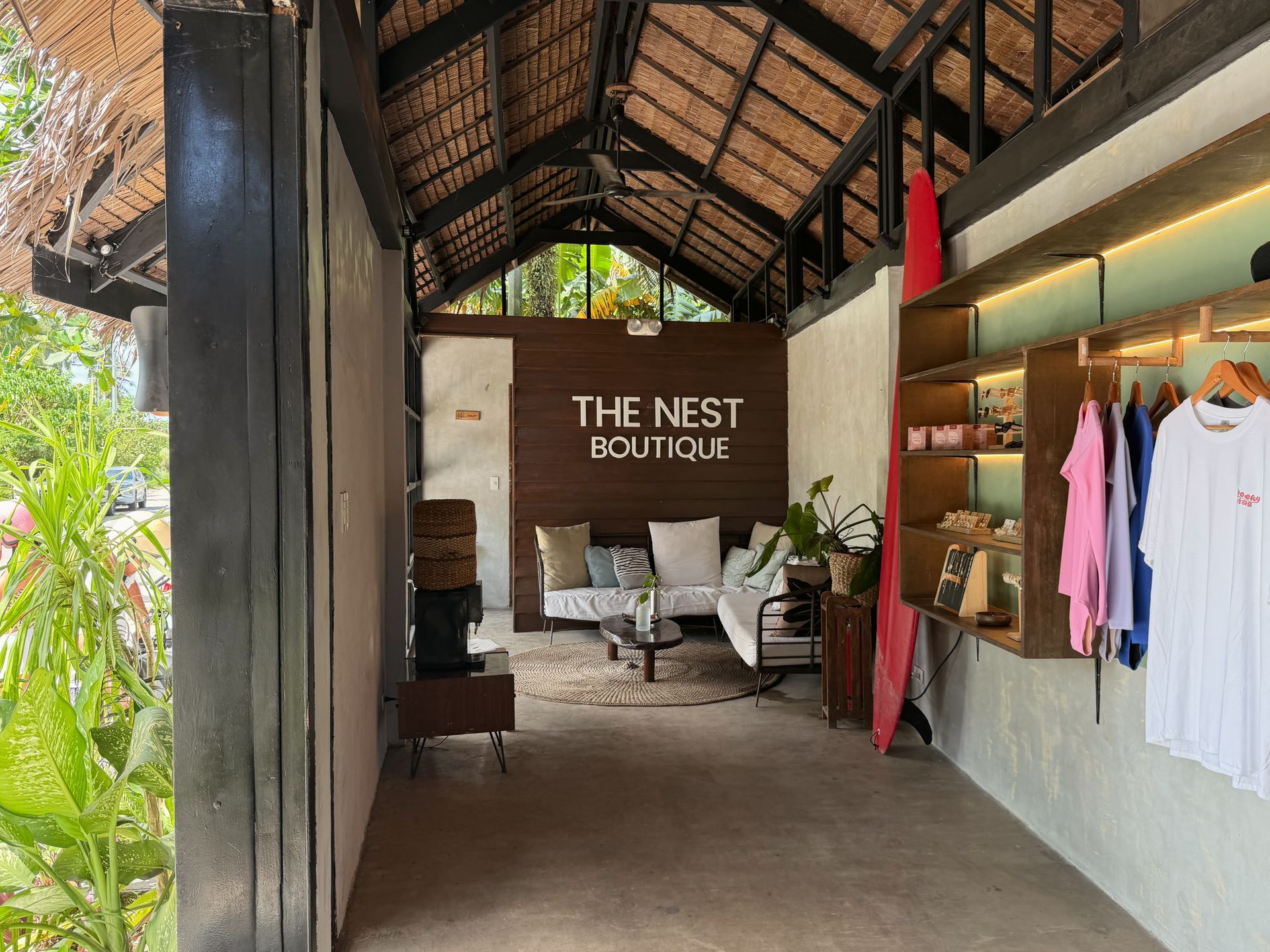 Boutique entrance with hanging clothes, plants, and a sign reading “The Nest Boutique”