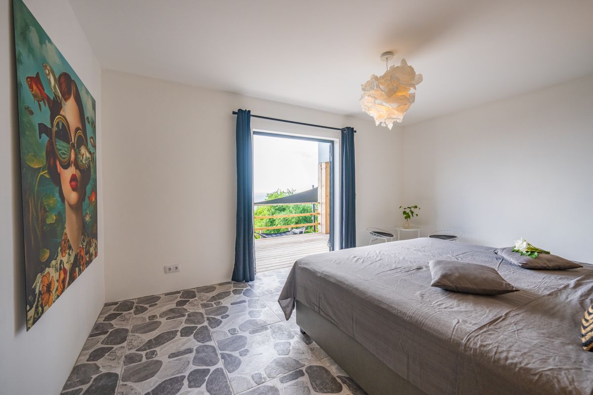 Slaapkamer met een groot bed, kunst en een deur die uitzicht biedt op een schilderachtig landschap.