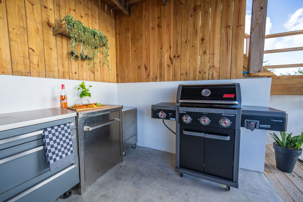 Buitenkeuken met grill, roestvrijstalen kasten en houten wanden.