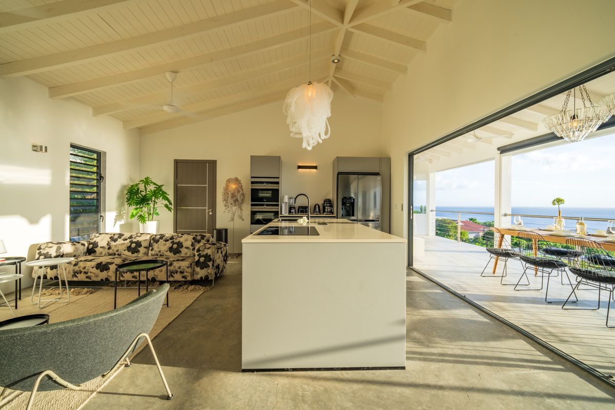 Ruime, moderne keuken en woonkamer met uitzicht op de oceaan. Open indeling, schuifdeuren en witte plafonds.