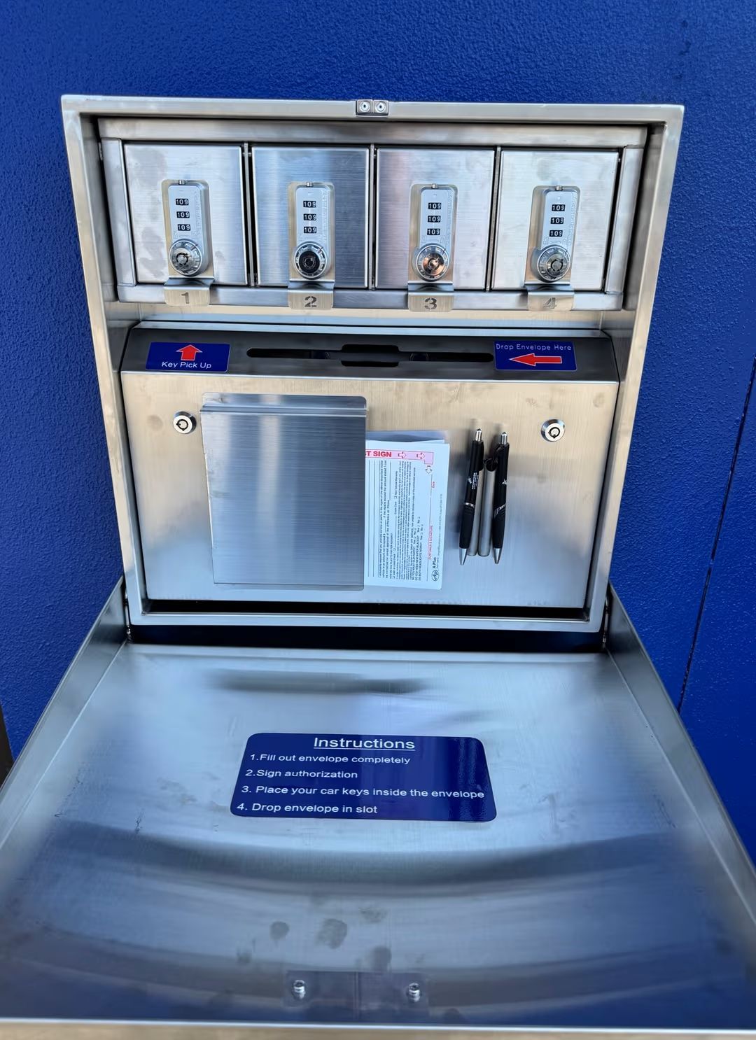 Stainless steel beverage station with cups, stirrers, and signs against a blue wall
