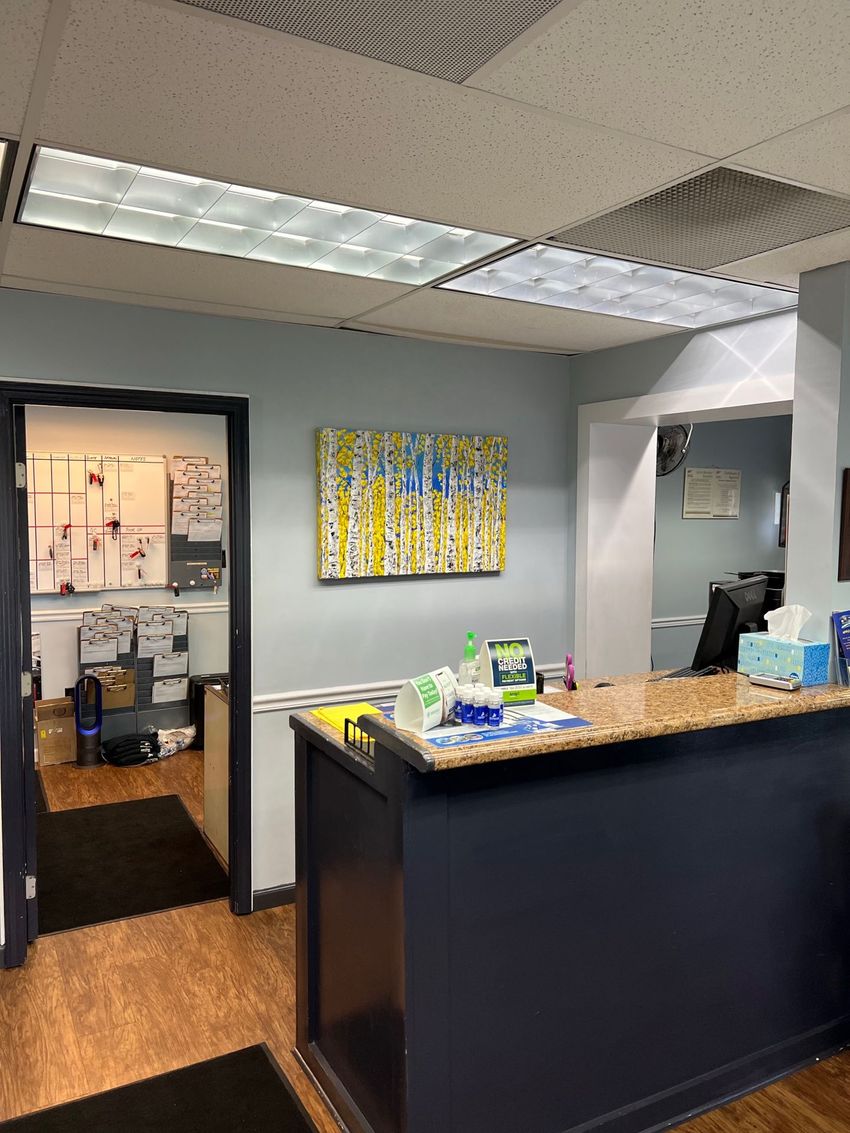 Modern office reception area with black front desk, gray walls, and colorful wall art.